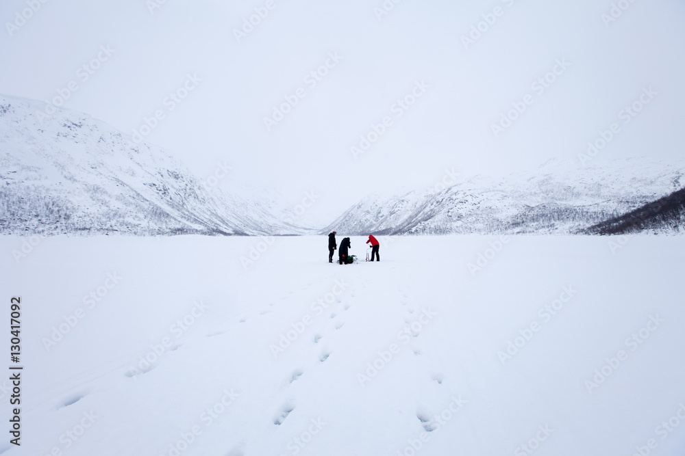 Ice fishing on frozen lake in the arctic alps in the Arctic Circle on Ringvassoya Island in the region of Tromso, Northern Norway Ice fishing on frozen lake in the arctic alps in the Arctic Circle on Ringvassoya Island in the region of Tromso, Northern Norway