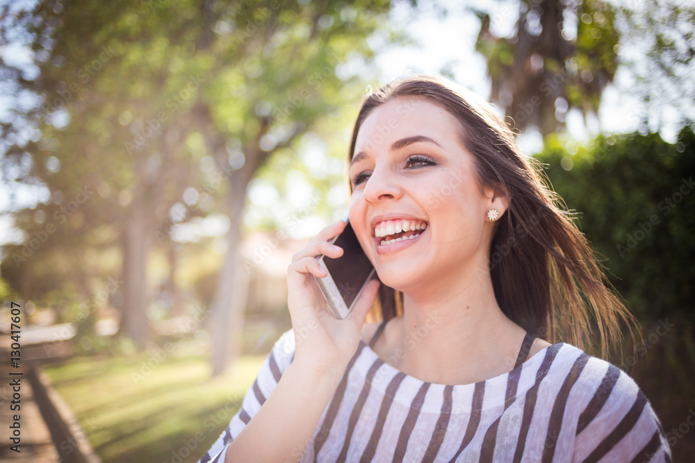 Pretty young millennial female model talking on her smart phone outside and taking selfies on her smart phone for social media Pretty young millennial female model talking on her smart phone outside and taking selfies on her smart phone for social media