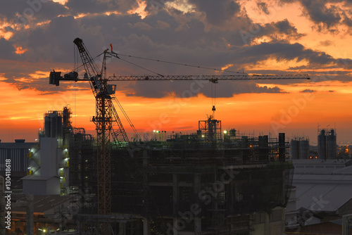 Silhouette tower cranes build large residential buildings at construction site .