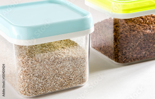 Food storage. Food ingredients (cut wheat and brown rice) in plastic containers. Selective focus.