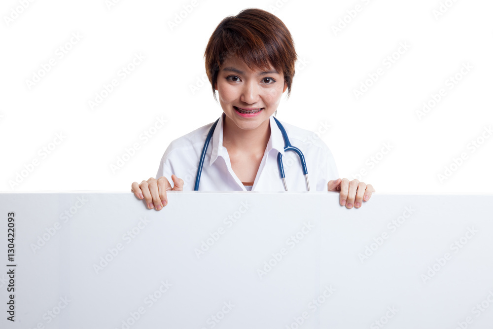 Young Asian female doctor show thumbs up behind blank white bil Young Asian female doctor show thumbs up behind blank white bil