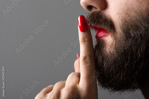 Bearded Man with Red Lipstick on His Lips and Nail Polish Making Silence Gesture
