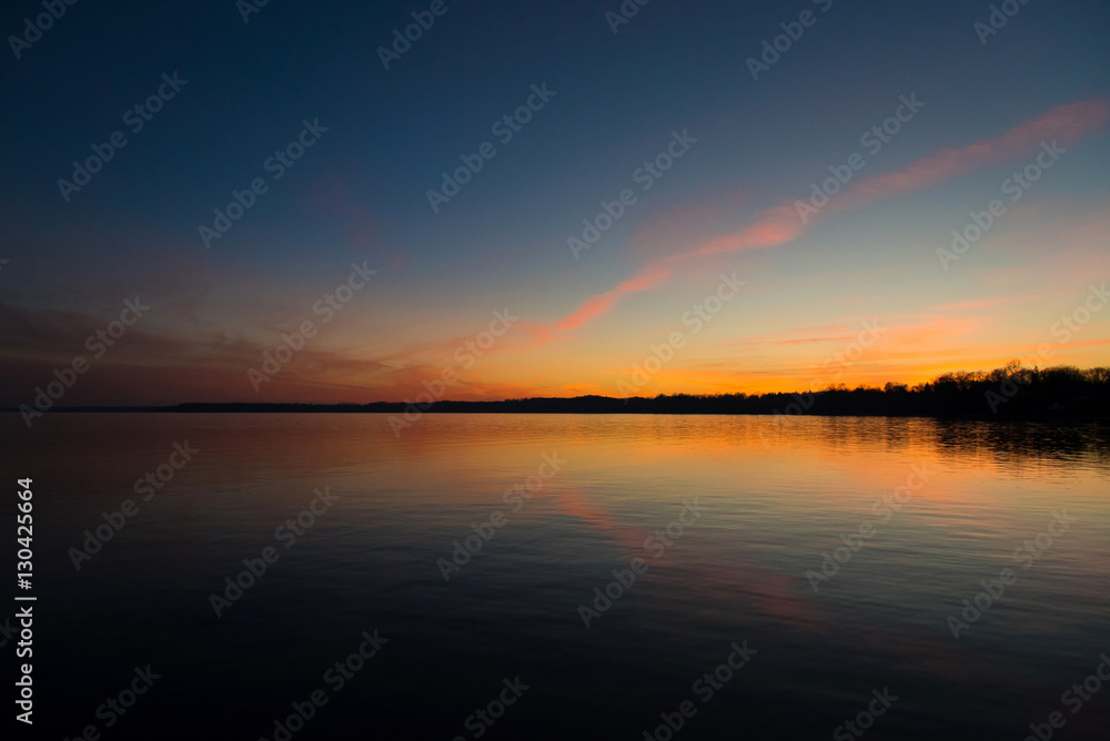 Obraz premium Sunset over the water with reflection off calm lake