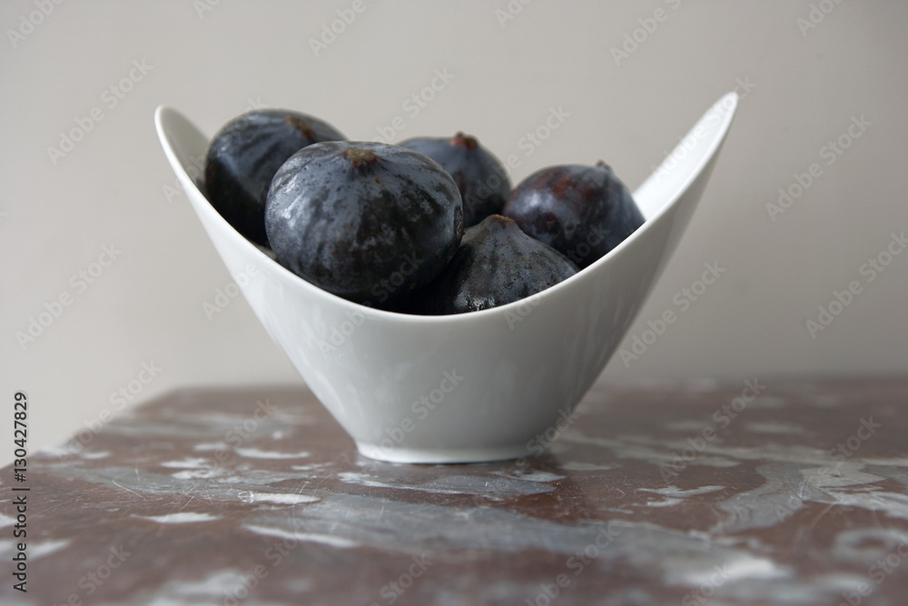 Obraz premium Figs in a White Bowl on a Marble Tabletop