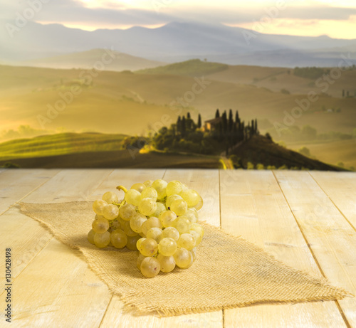 Grapes bright on wooden background, background Tuscan landscape