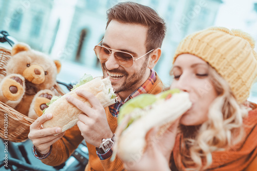 Happy young couple eating sandwich