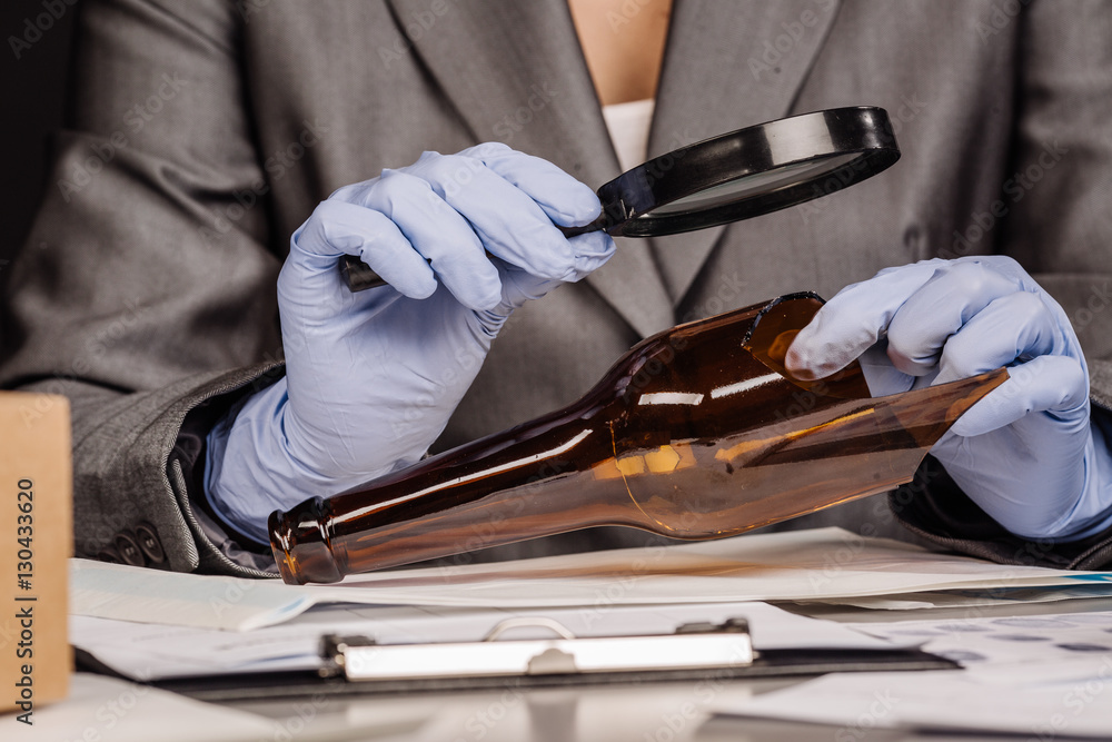 Fototapeta premium Detective through a magnifying glass looking at a evidence