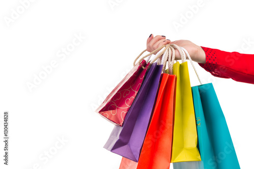 Versicolored and bright shopping packages hanging on female red-sleeved arm