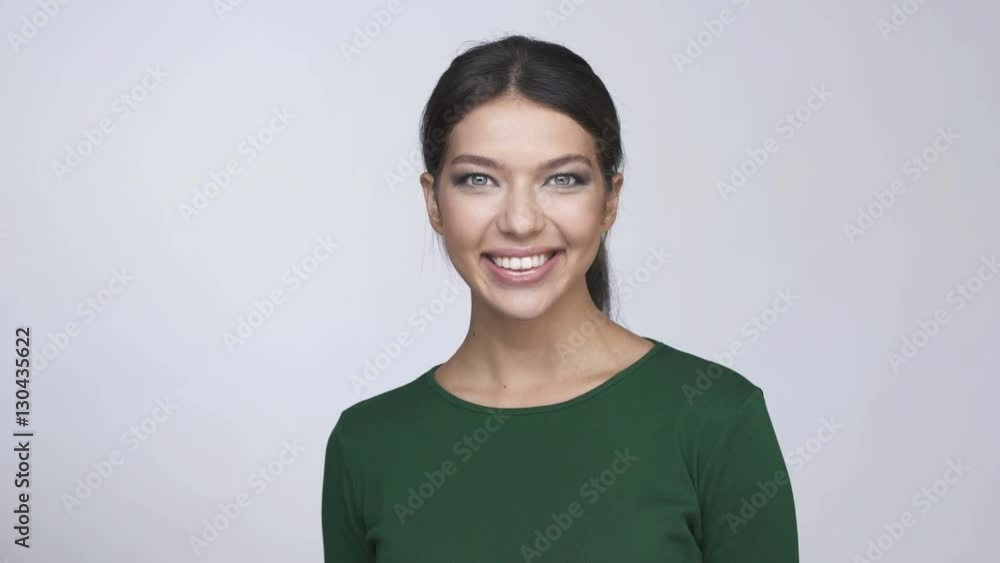 Cheerful pretty young brunette woman in green sweater looking at camera and smiling Cheerful pretty young brunette woman in green sweater looking at camera and smiling