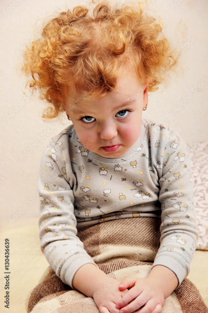 Fototapeta premium Cute red hairs curly liitle girl dressed in pajamas puffing His Cheeks.Selective focus