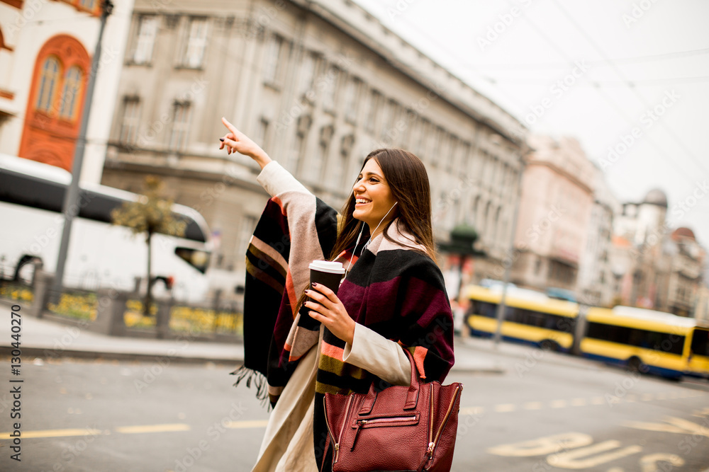 Fototapeta premium Młoda kobieta przywołuje taksówkę na ulicy w mieście