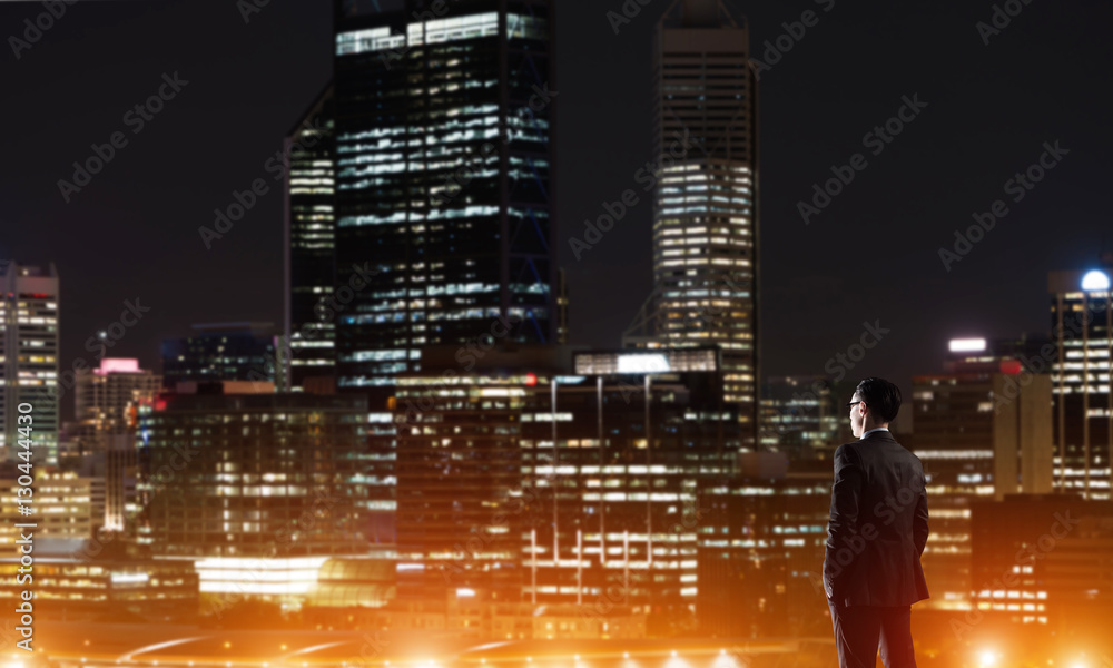 Businessman viewing night glowing city Businessman viewing night glowing city