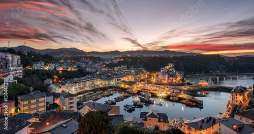Touristic destination Luarca, Asturias, Spain, Europe. Nature urban landscape with fishing and pleasure port with boats, harbor, sea and beach. Gorgeous red sky at sunset with beautiful sky clouds.