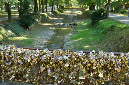 Foto Bridge of Love with lots of padlocks and rivulet with trees on riversides in Vrn