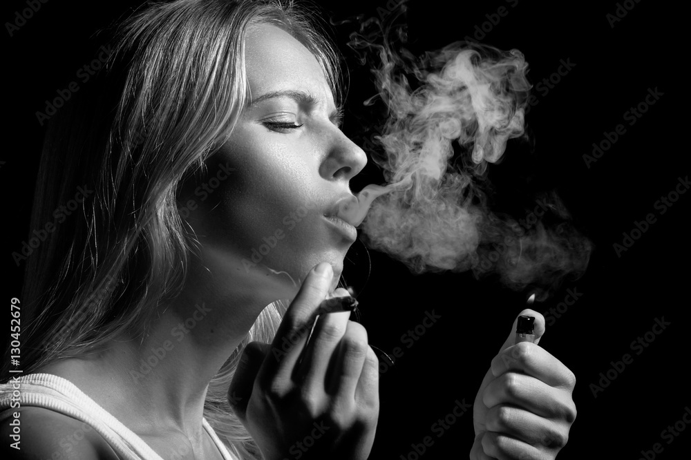 Fototapeta premium blond young woman smoking on black background, monochrome