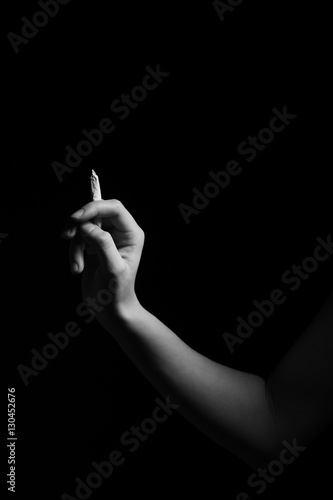 female hand with joint of marijuana on black background monochrome