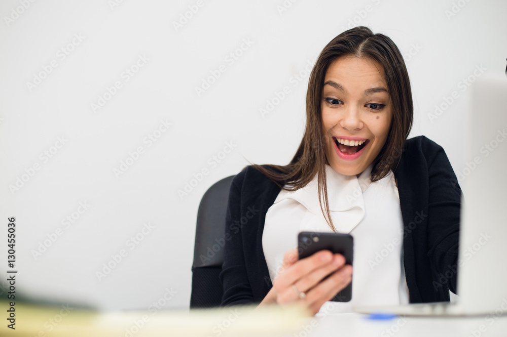 Happy surprising woman looking in mobile phone and reading message with open mouth Happy surprising woman looking in mobile phone and reading message with open mouth