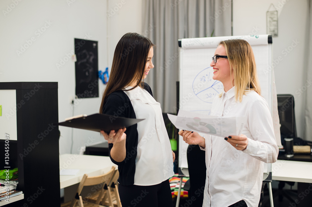 Obraz premium Two beautiful young executives reading some papers