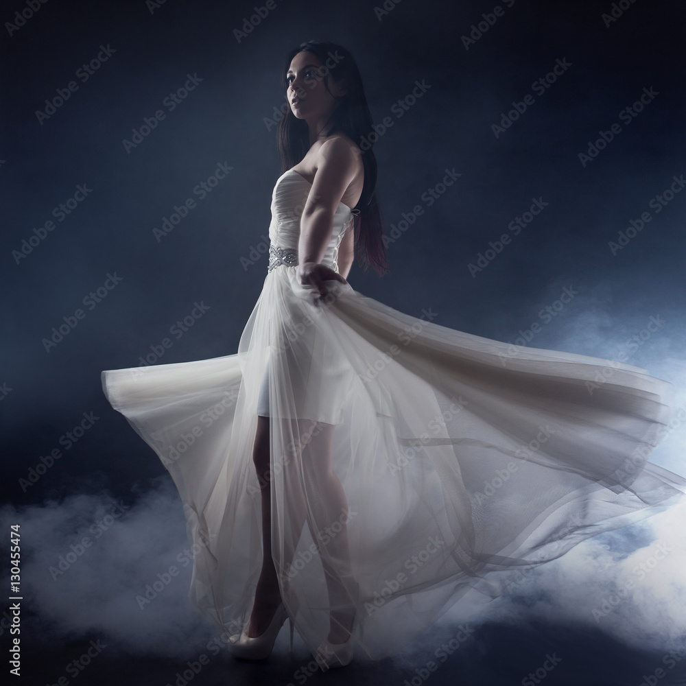 Beautiful sexy young woman. Portrait of girl in long white dress, mystical, mysterious style, dark background Beautiful sexy young woman. Portrait of girl in long white dress, mystical, mysterious style, dark background
