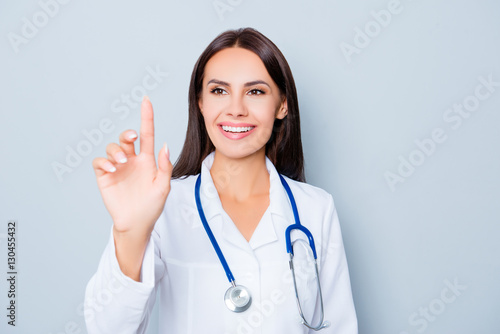 Young happy female doctor touching virtual screen