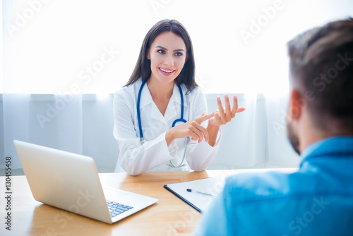 Friendly female doctor consulting her patient and counting disea photo