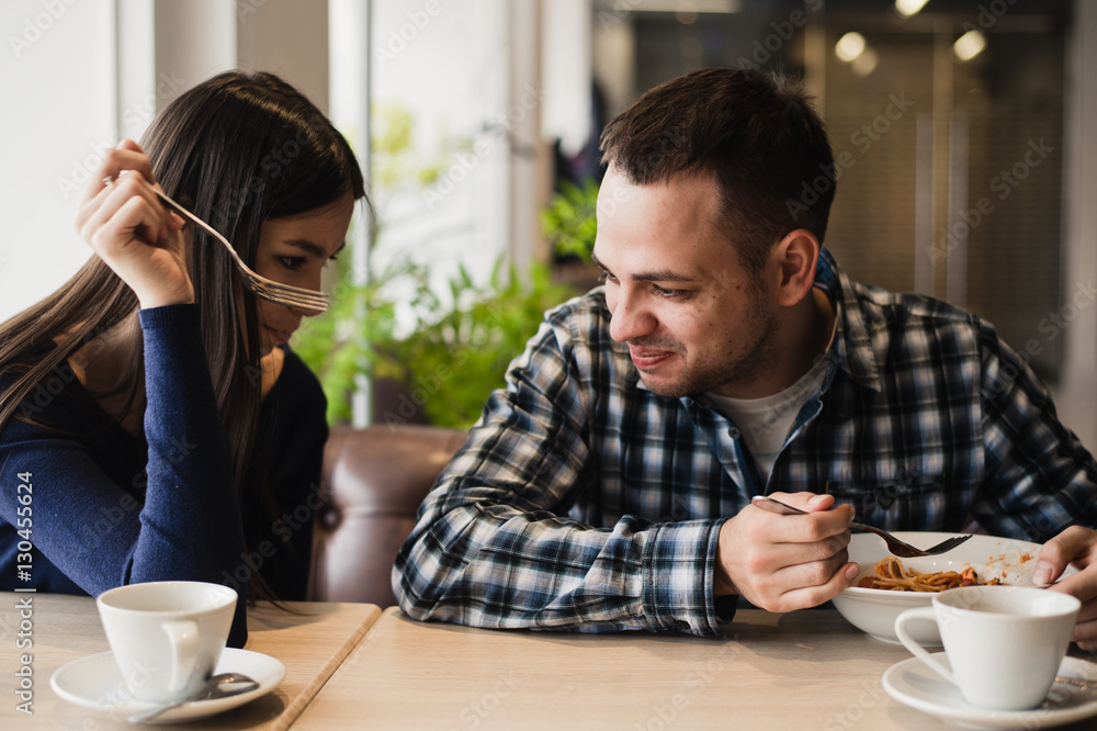 Funny couple eating noodles in cafe. He don't want to share his food with girlfriend foto de