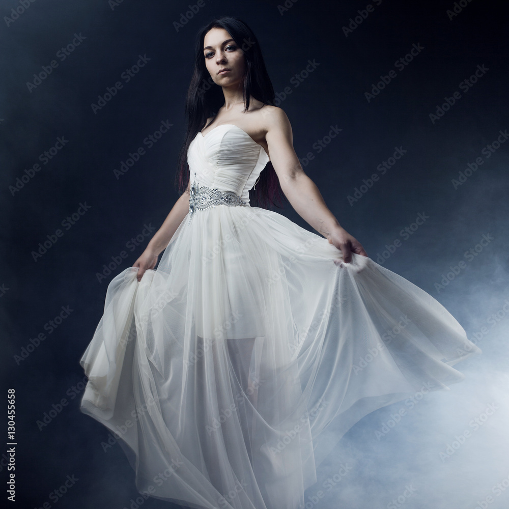 Beautiful sexy young woman. Portrait of girl in long white dress, mystical, mysterious style, dark background Beautiful sexy young woman. Portrait of girl in long white dress, mystical, mysterious style, dark background