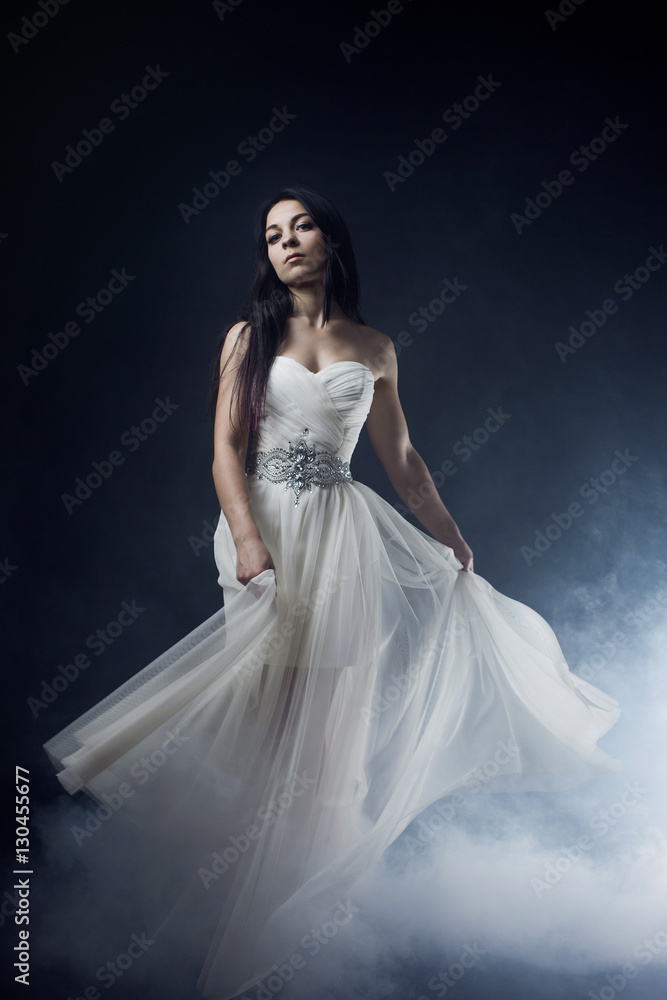 Beautiful sexy young woman. Portrait of girl in long white dress, mystical, mysterious style, dark background