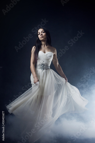 Beautiful sexy young woman. Portrait of girl in long white dress, mystical, mysterious style, dark background