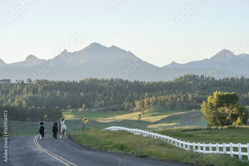 Girls bareback riding horses on rural mountain road