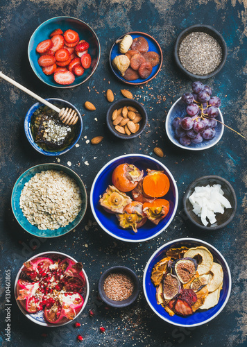 Ingredients for healthy breakfast over dark blue background, top view. Fresh and dried fruit, chia seeds, oatmeal, nuts, honey. Clean eating, vegan, vegetarian, healthy food, detox and dieting concept