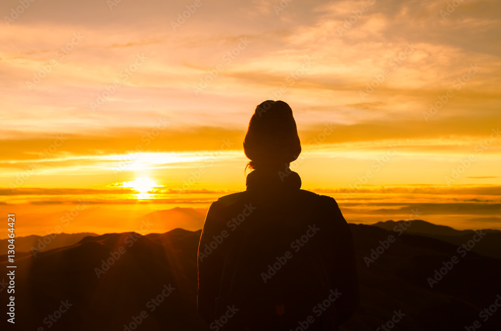 Woman watching the sunrise high up on a mountain. 