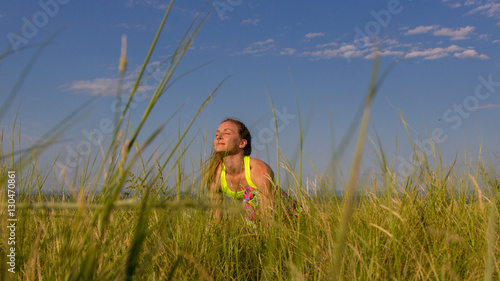 Young girl in colored clothing makes yoga on a mountain