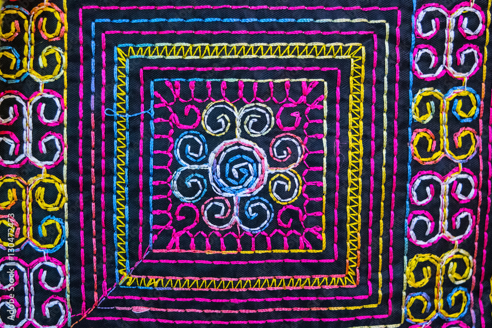 Colorful folk embroidery at black fabric close up