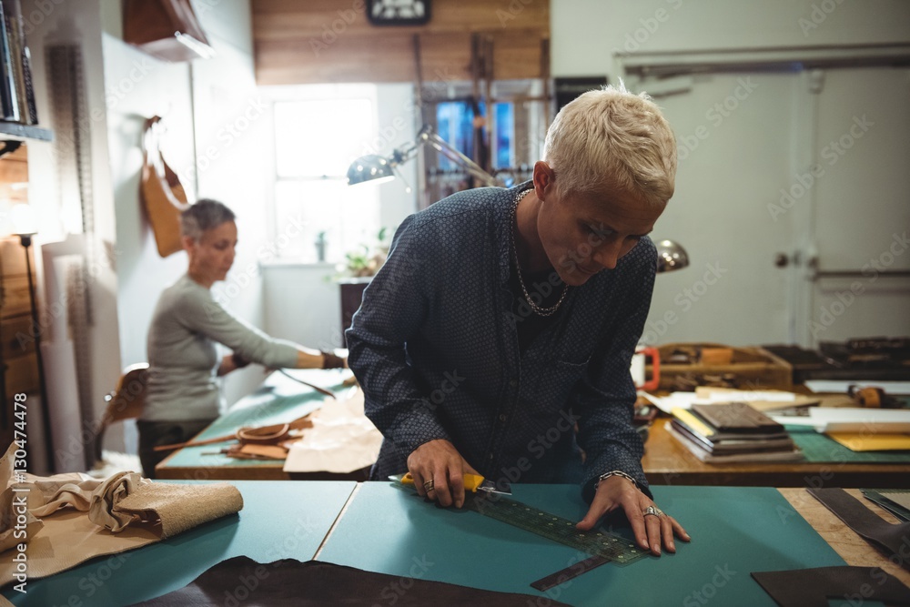 Attentive craftswoman cutting leather Attentive craftswoman cutting leather