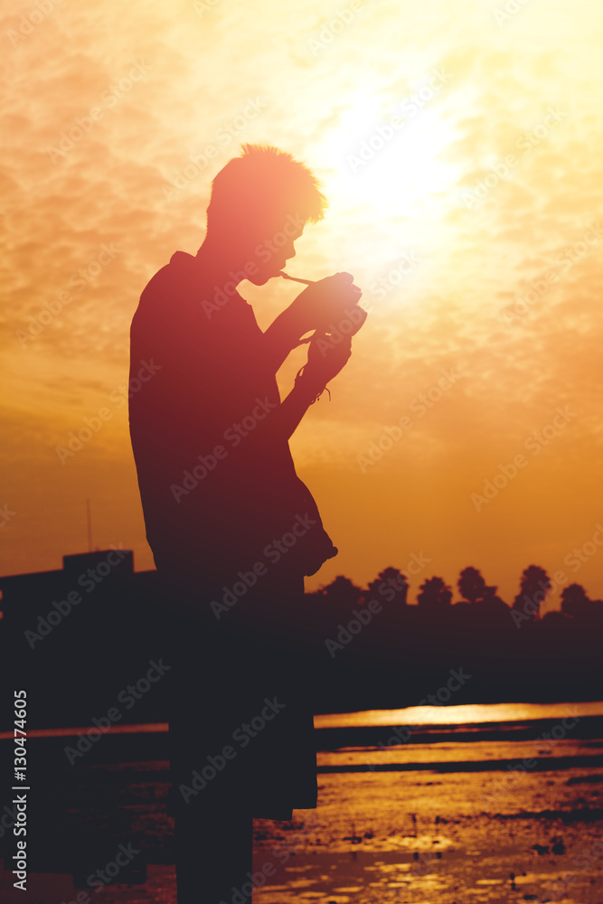 Silhouette of young photographer holding a camera on sunset.