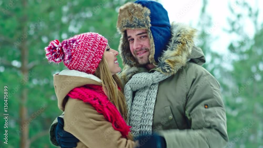 Closeup of young loving couple hugging, kissing and posing at camera at winter day outdoor Closeup of young loving couple hugging, kissing and posing at camera at winter day outdoor