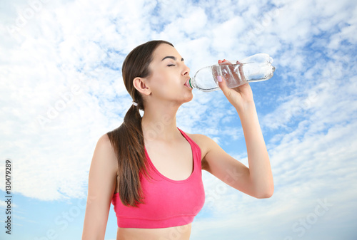 Young woman drinking water after run. Sport and healthy lifestyle concept.