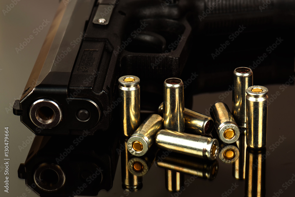 Fototapeta premium The black gun and cartridges to him on a black background close up.