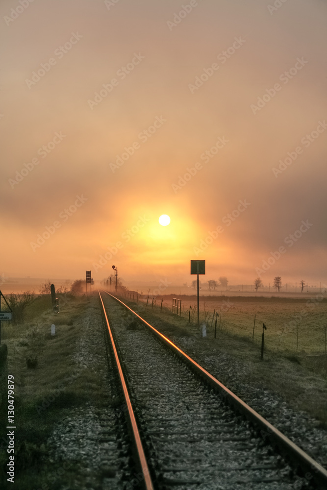 Winter sunrise reflected on the railroad.The beginning of a new day is lost at the vanishing point of the rails.Italy,Apulia.