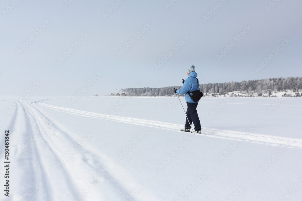The woman in a blue jacket skiing on the snow of the river