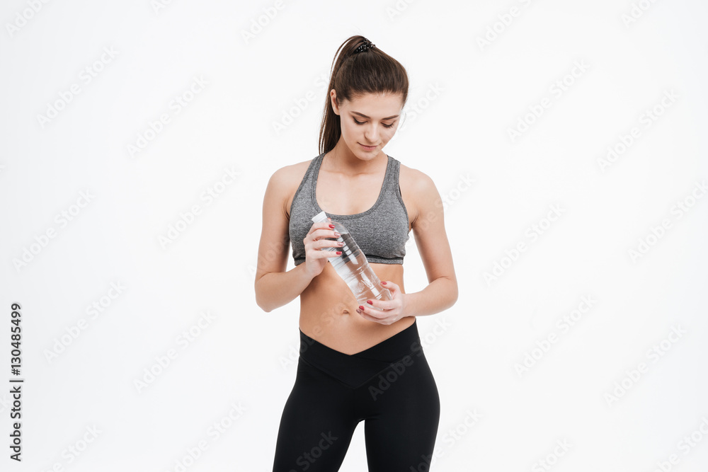 Pretty young sports woman holding water bottle and looking down Pretty young sports woman holding water bottle and looking down