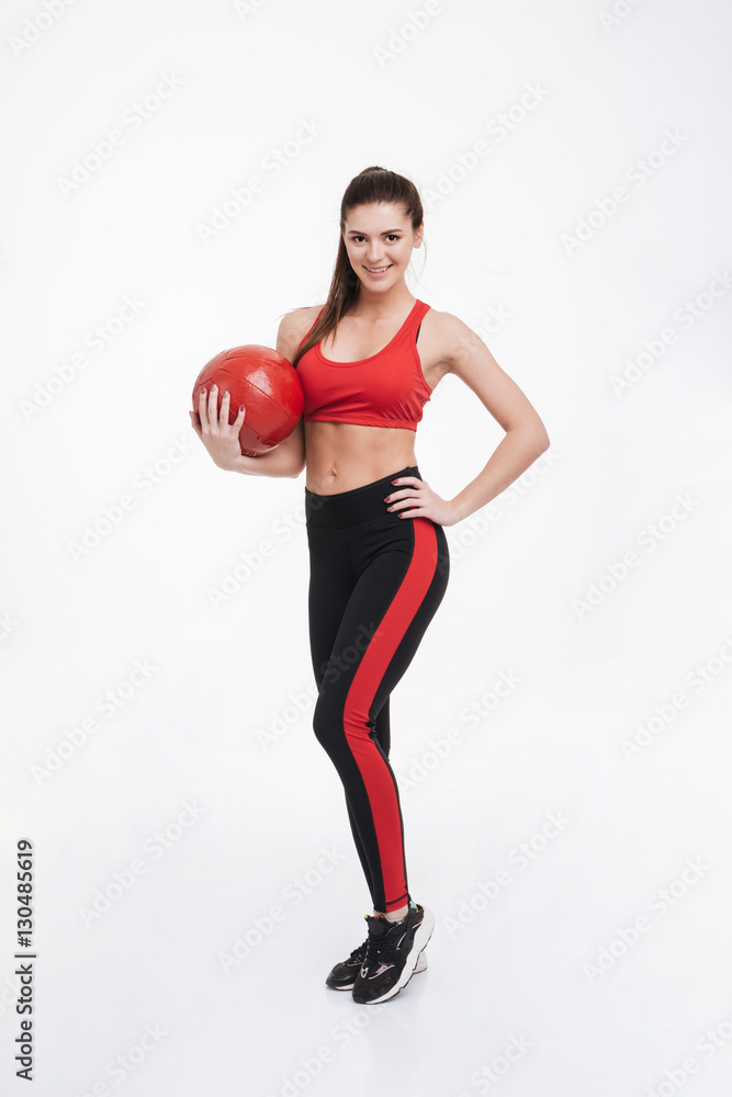 Happy smiling fitness woman standing and holding red weight ball