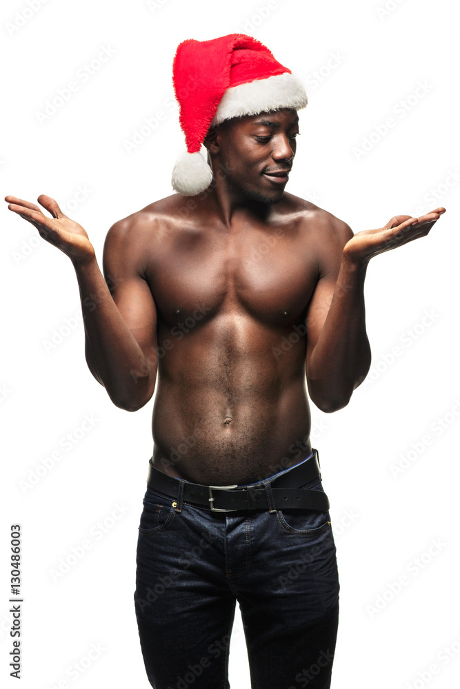 Muscular black shirtless young man in Santa Claus hat - obrazy, fototapety, plakaty 
