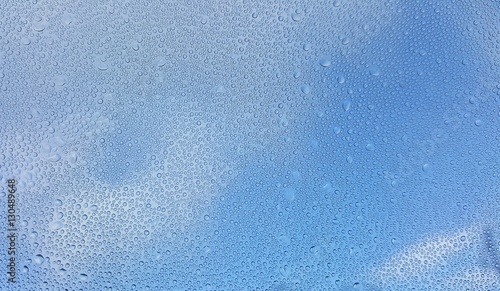 Water drops on glass with blurred blue sky background
