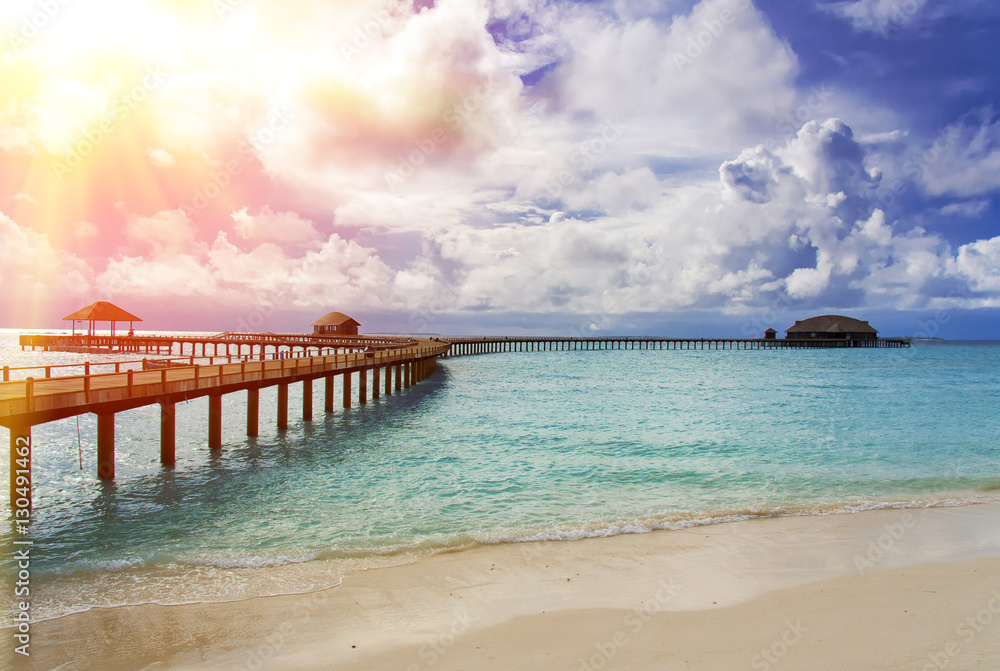 Maldives. The turquoise sea in sunshine and the wooden bridge over water
