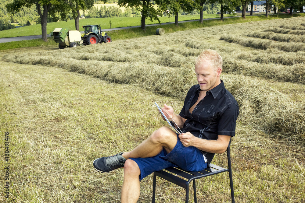Fototapeta premium Man with tablet PC in haymaking