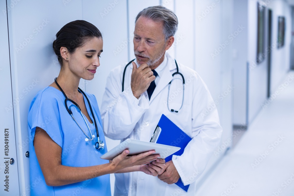Doctor and colleague discussing over tablet Doctor and colleague discussing over tablet