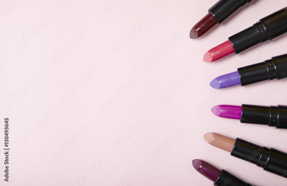Aerial view of assorted lipstick make up arranged on a pastel pink background with blank space at side Aerial view of assorted lipstick make up arranged on a pastel pink background with blank space at side