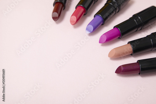 Lipstick make up arranged on a pastel pink background forming a page header with blank space at side